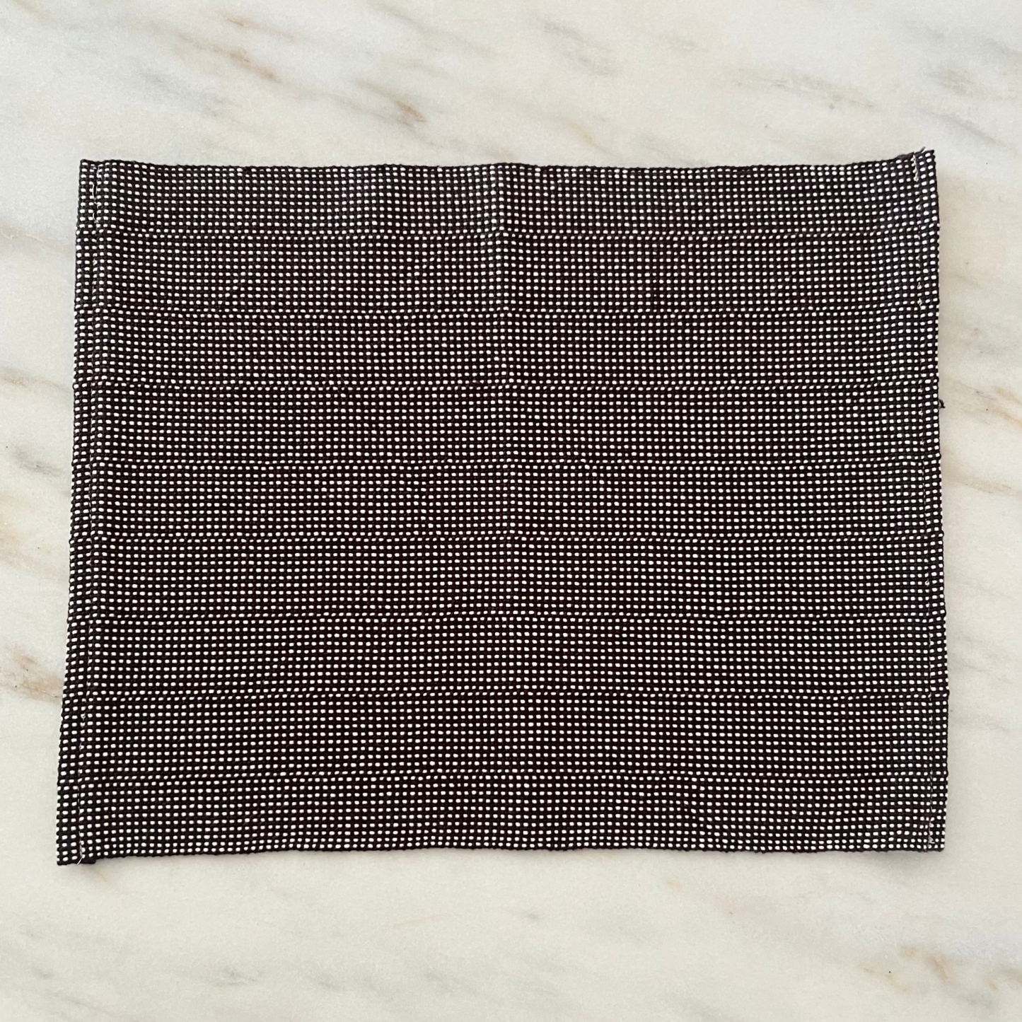 brown and white checkered fabric on a marble surface