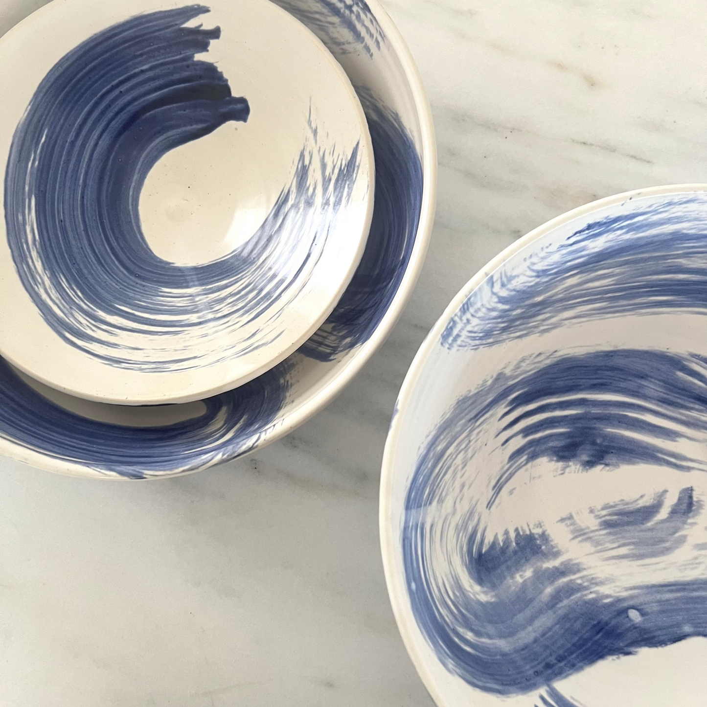 Two ceramic bowls with blue wave patterns on a marble surface