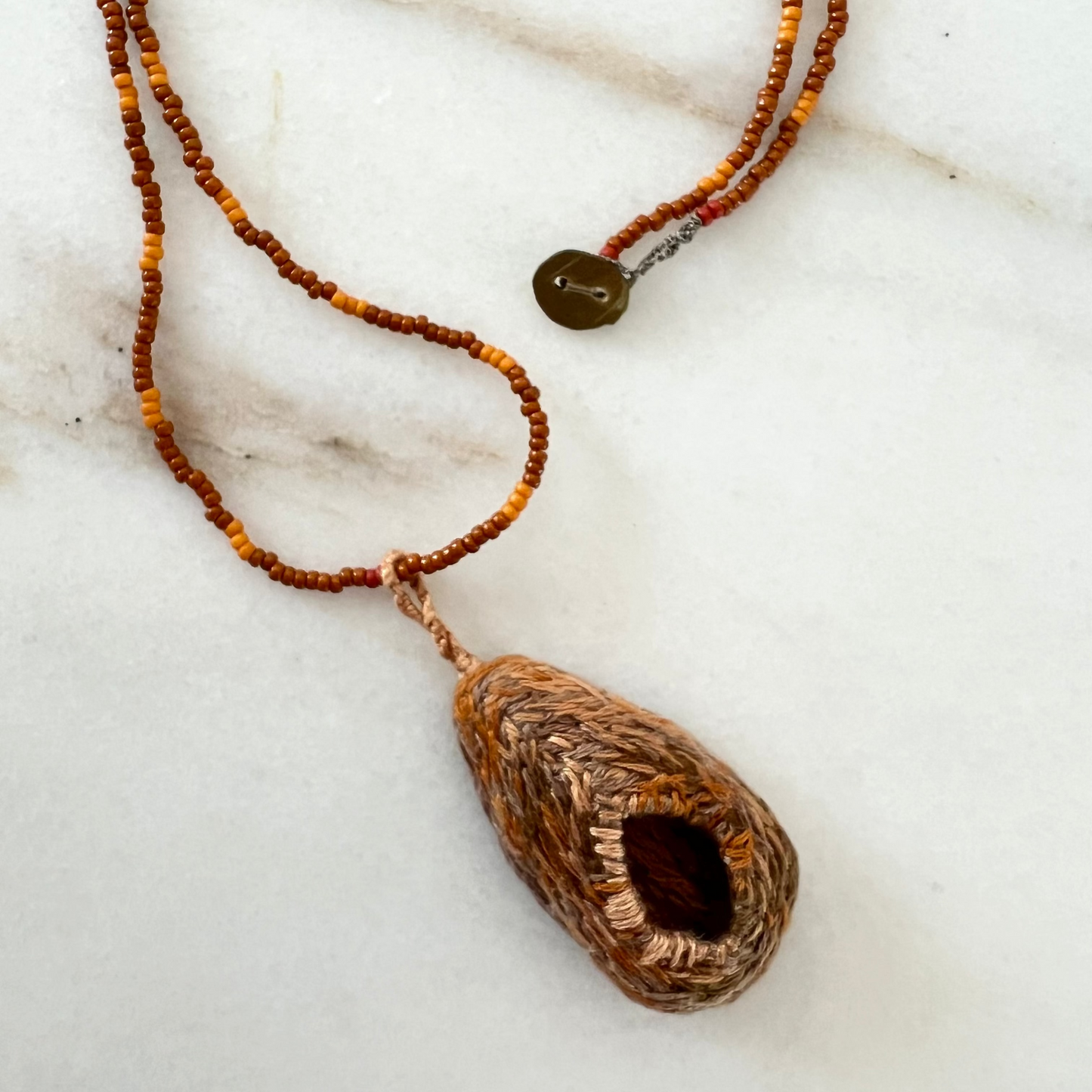 Necklace with a textured pendant on a marble surface