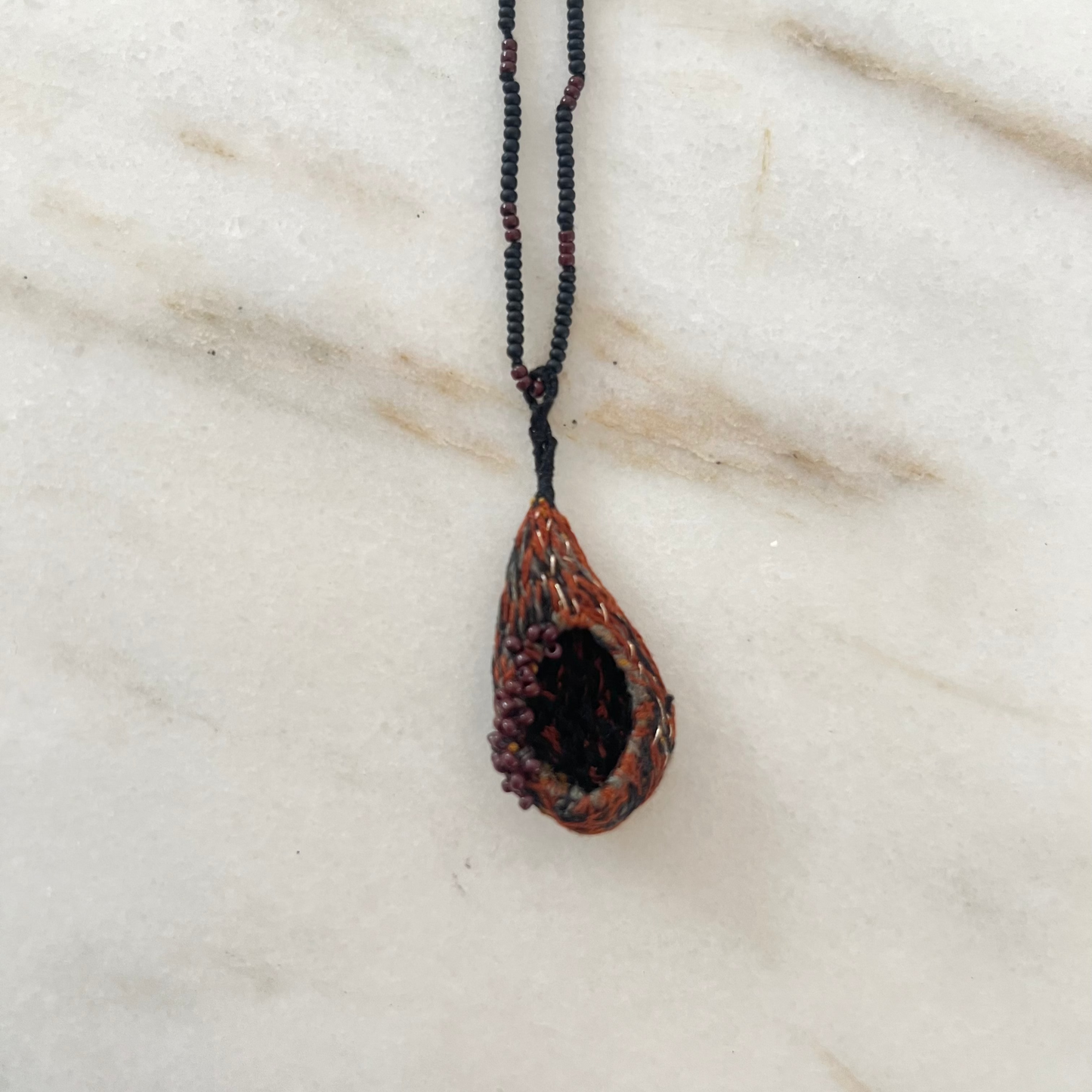 embroidered pendant necklace on a marble surface