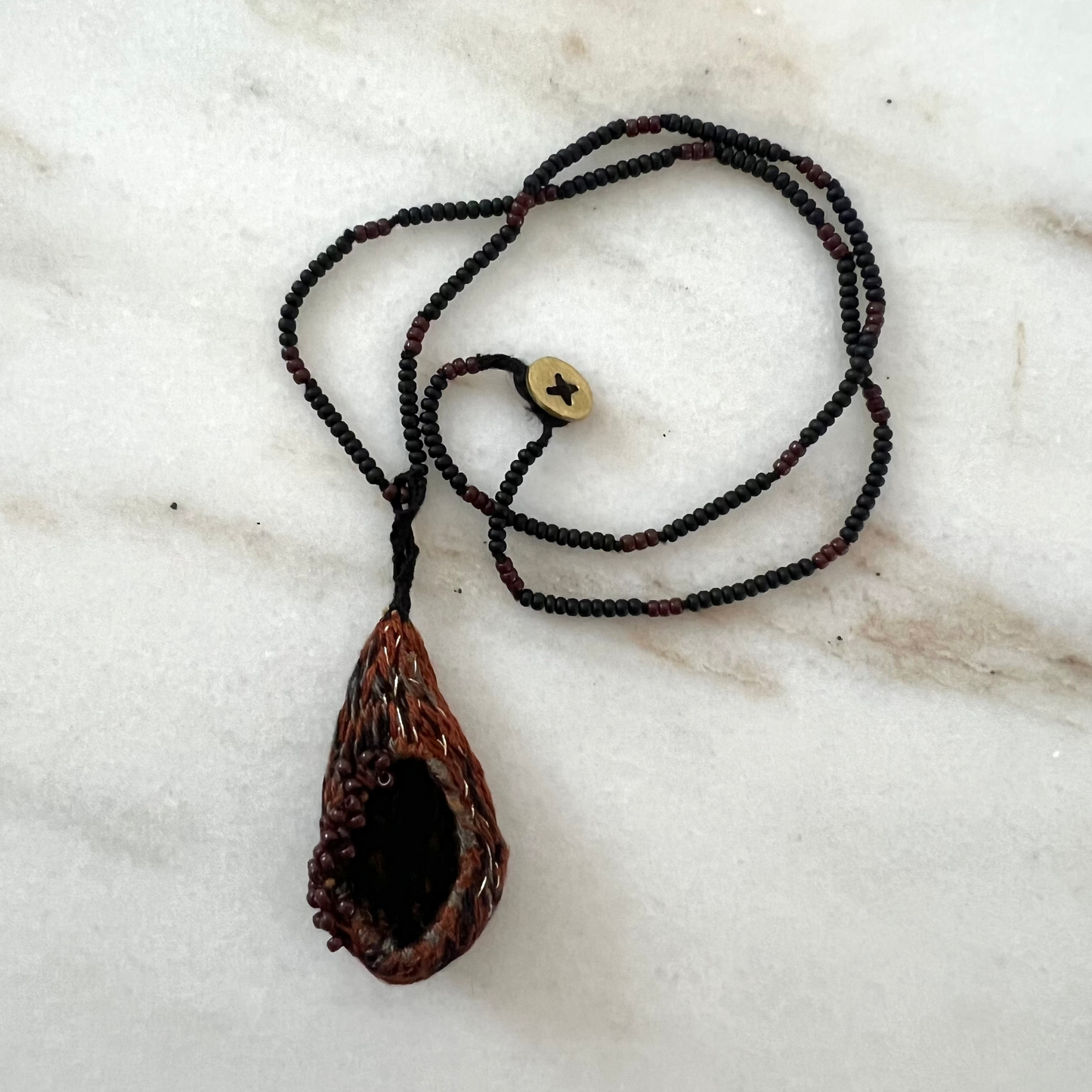 Embroidered pendant necklace on a marble surface