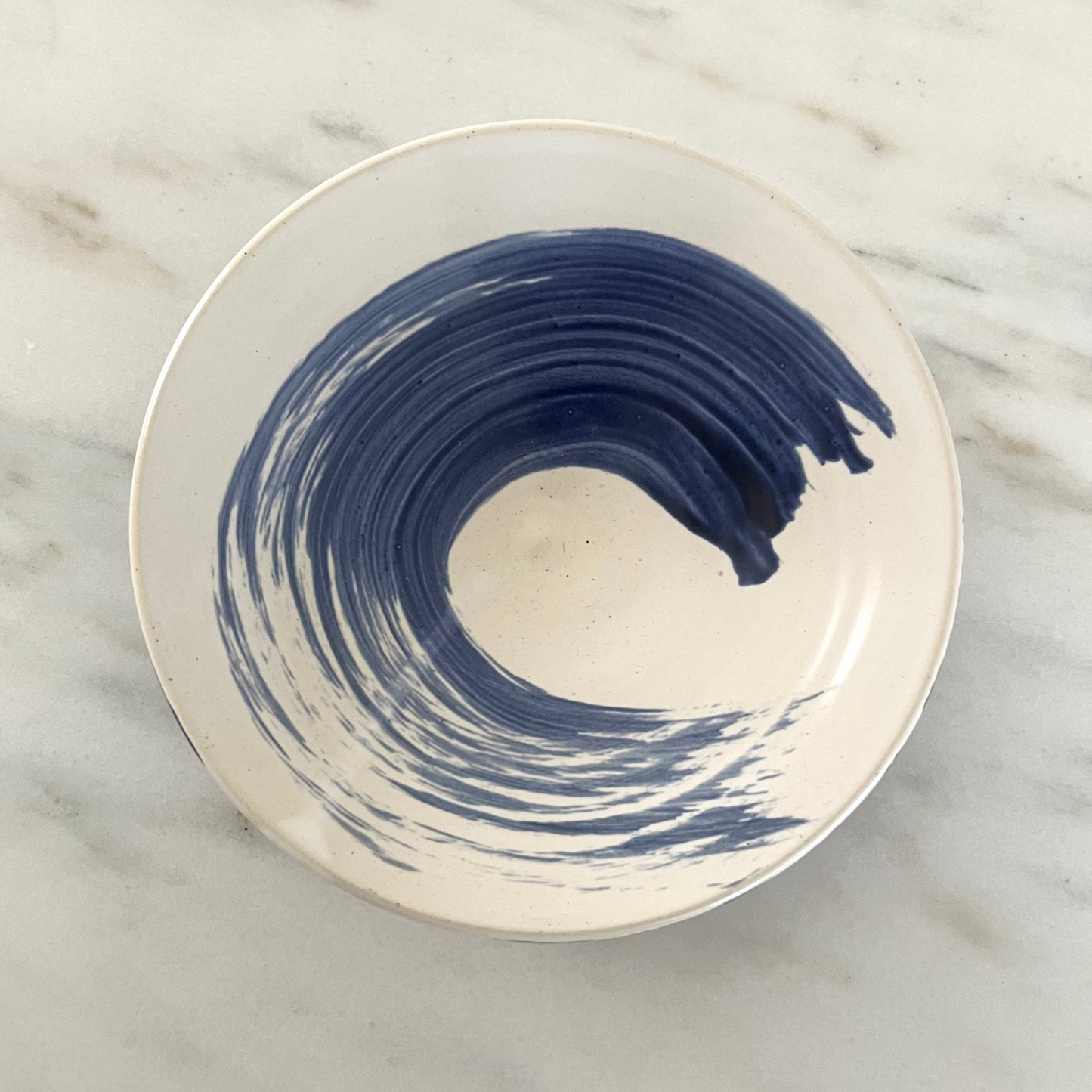 Ceramic plate with blue wave design on a marble surface