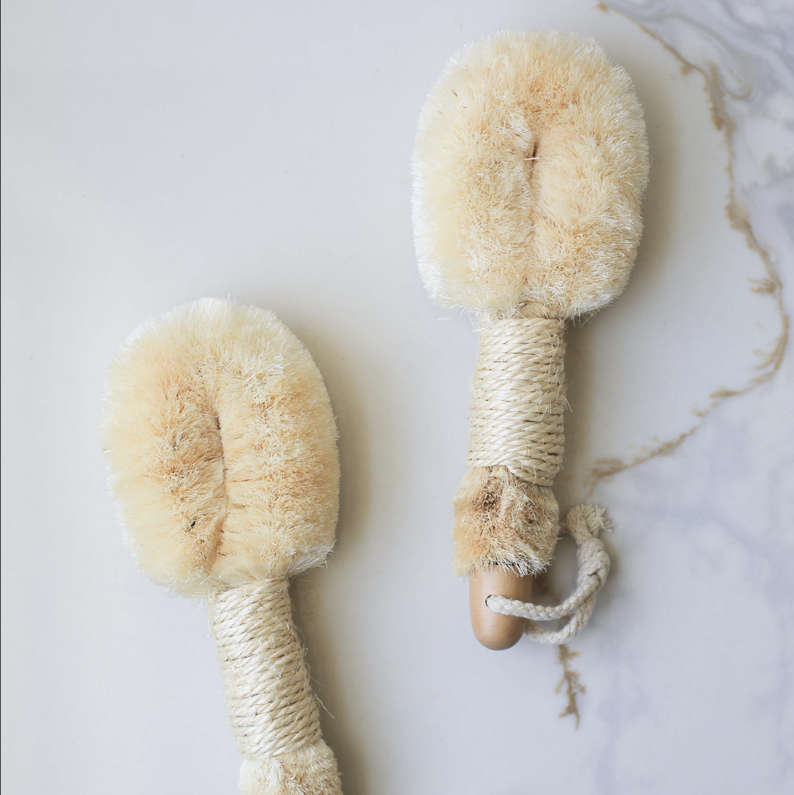 Two natural body brushes on a marble surface