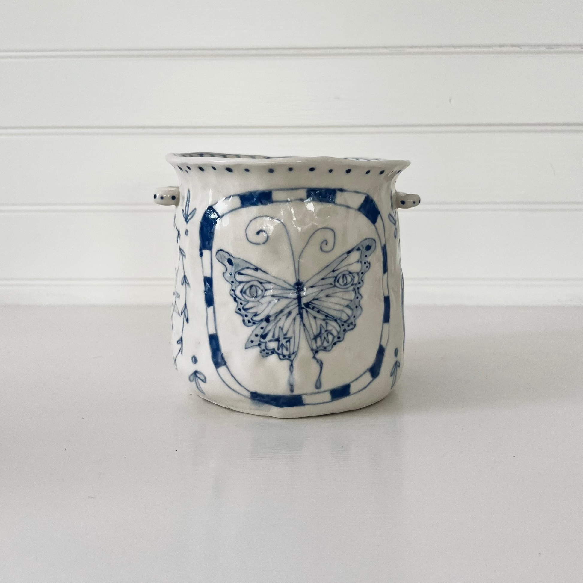 Ceramic planter with blue butterfly design on a white background