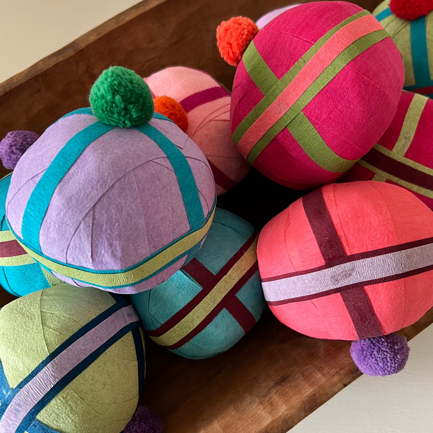 Colorful spherical pillows with pom-poms on a wooden surface