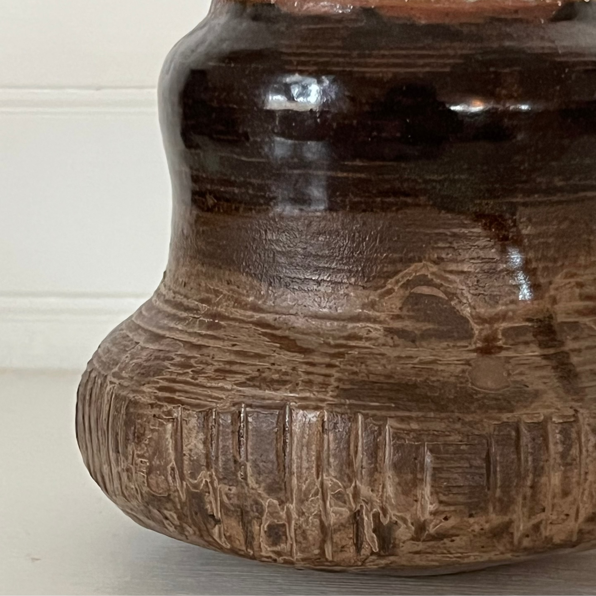 Brown ceramic pot with textured design on a light background