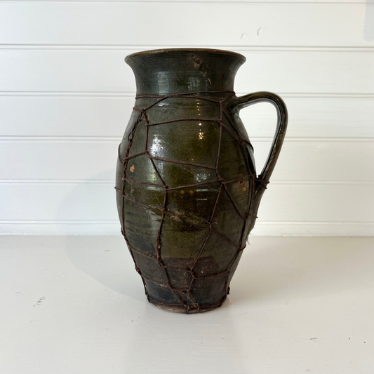 Vintage ceramic pitcher with cracked surface on a white background