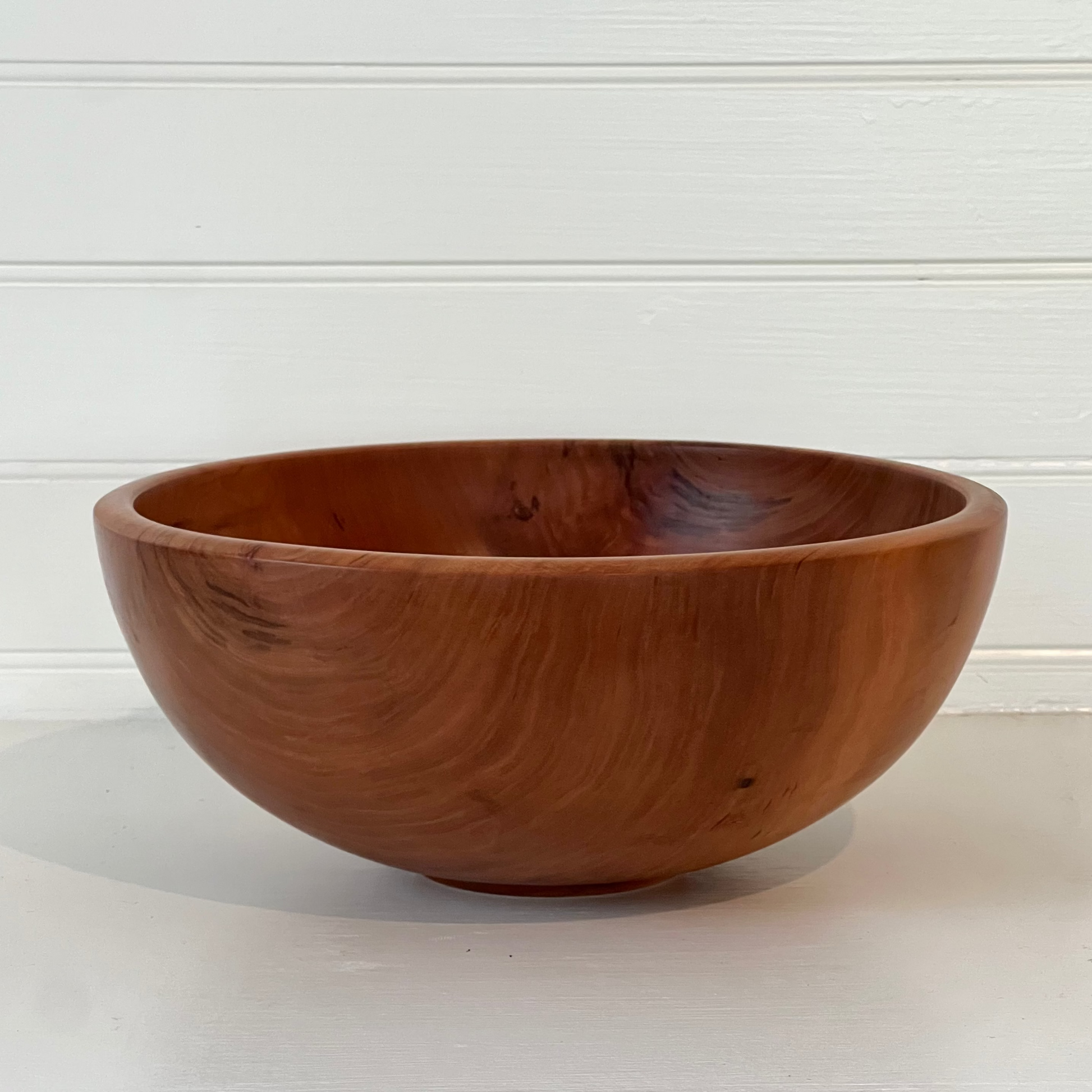 Wooden bowl on a white surface with a light gray background