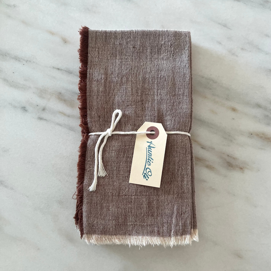 Brown fabric napkin with a tag on a marble surface