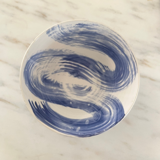 White plate with blue abstract design on a marble surface