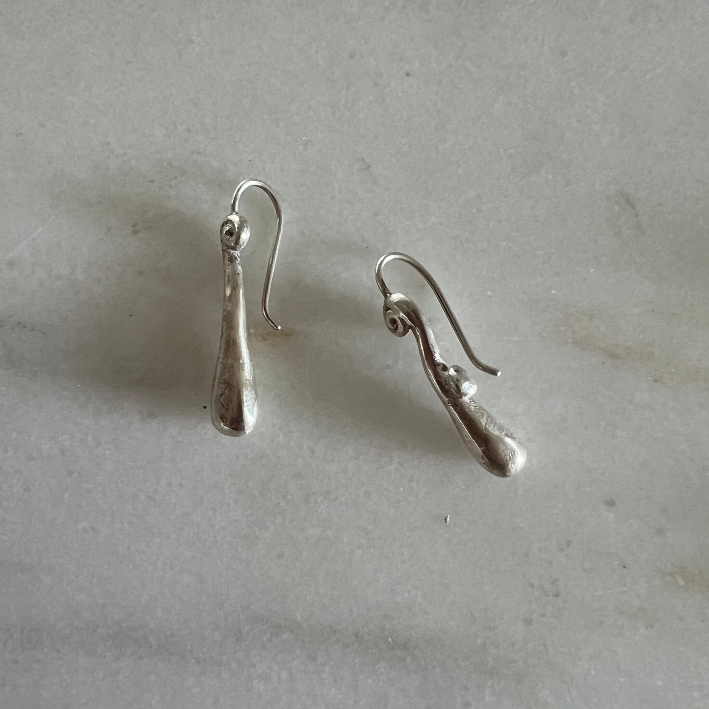 Pair of silver earrings on a light gray surface