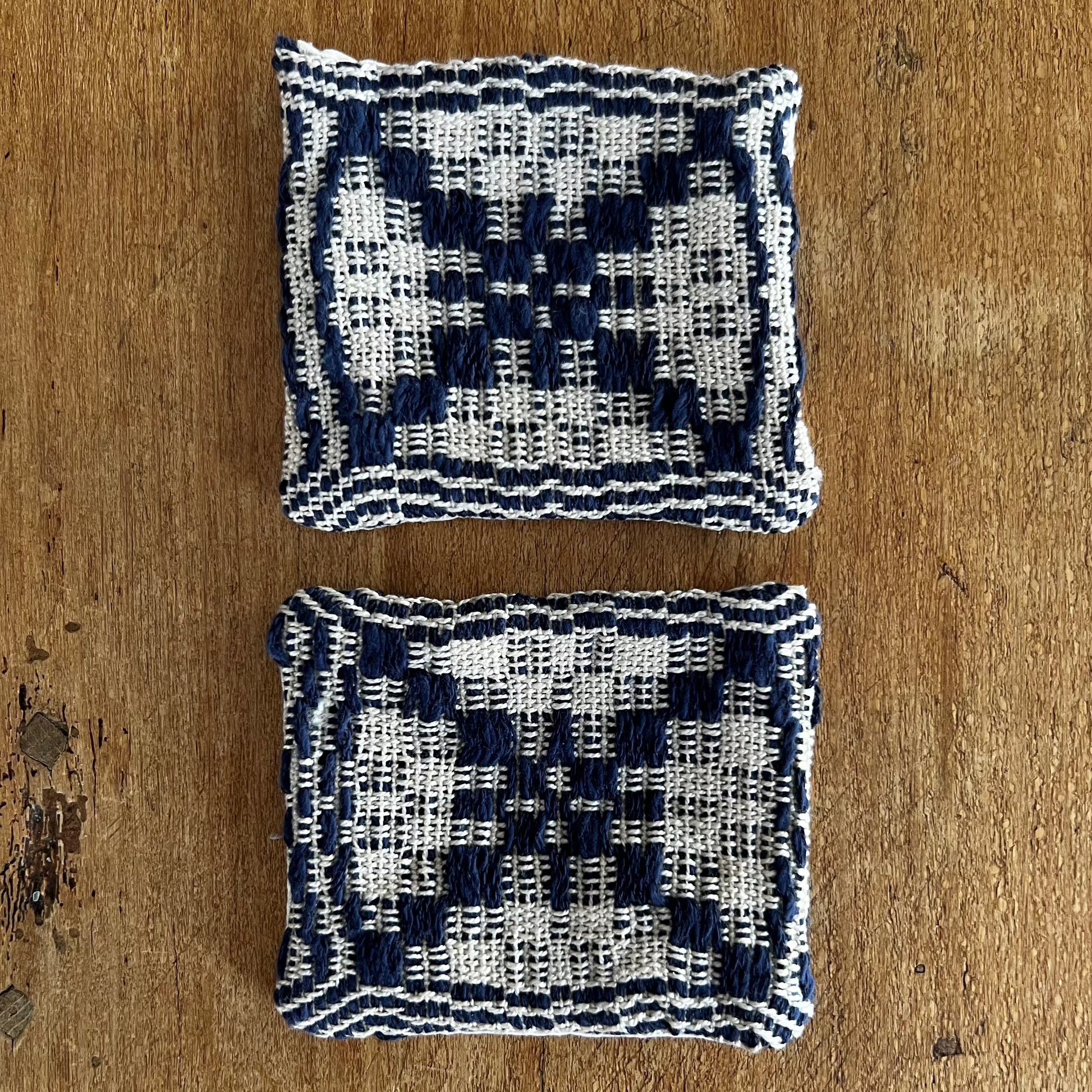 Two woven coasters with a geometric pattern on a wooden surface