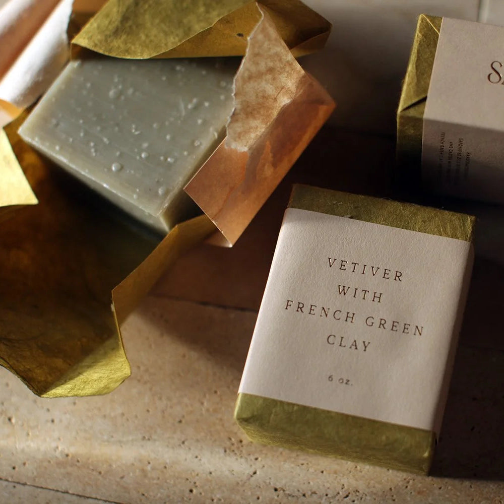 Two soap bars and their packaging on a stone surface with 'SAIPUA' branding.